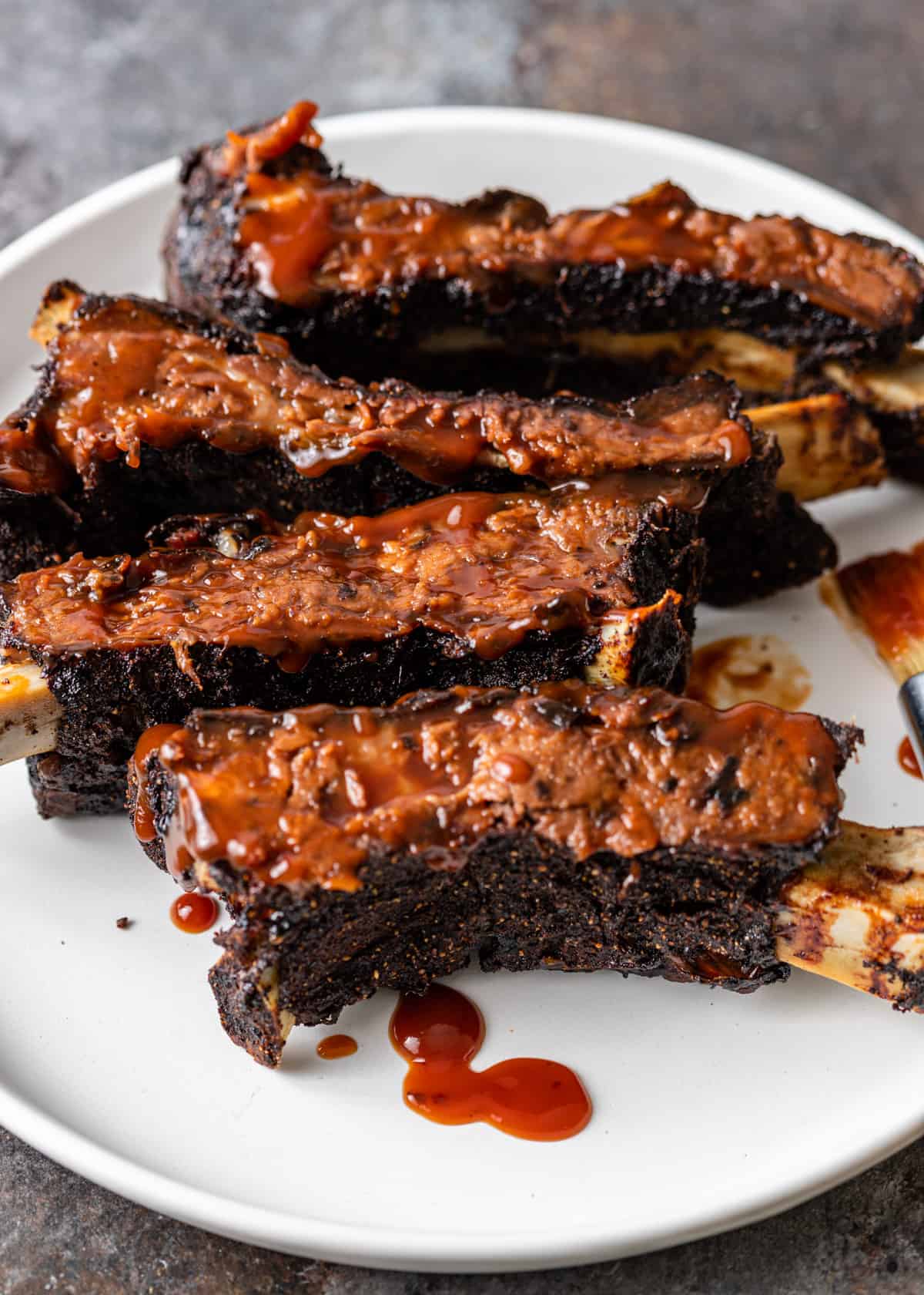 a plate of crispy smoked beef back ribs smothered in barbecue sauce