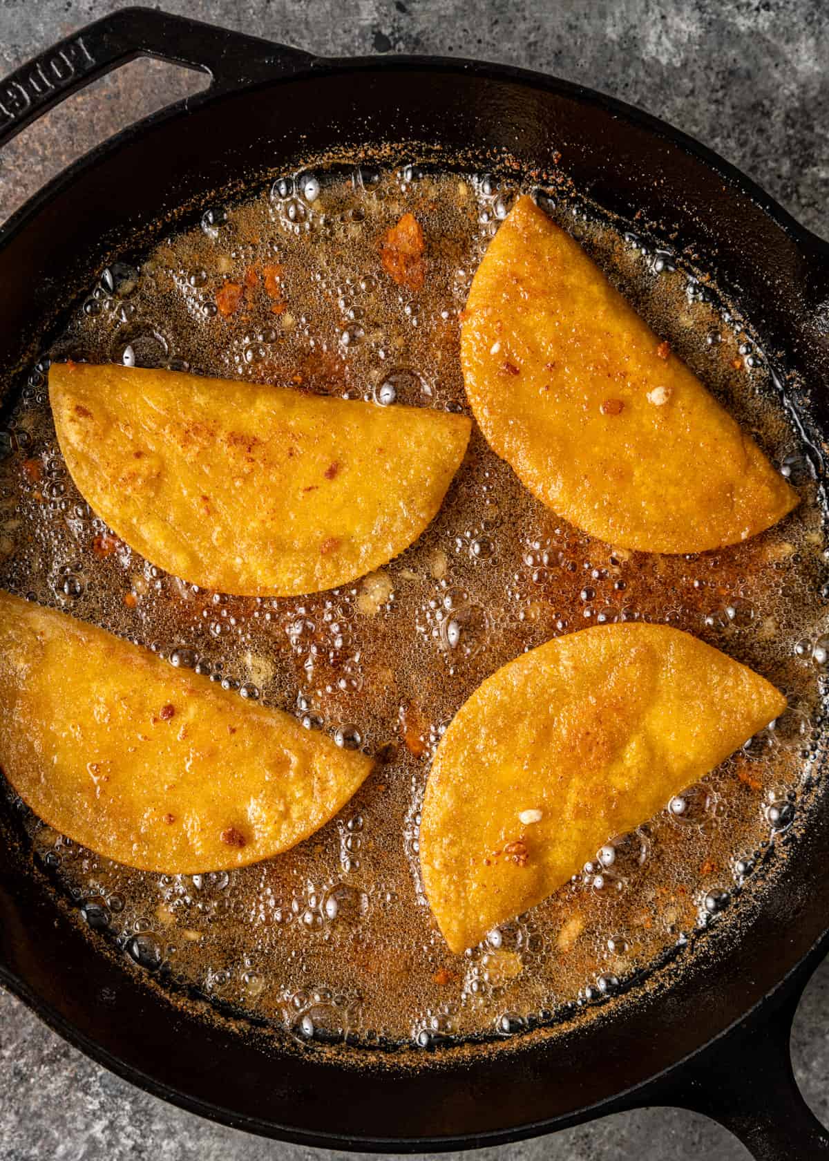 overhead: pan frying potato tacos in a skillet
