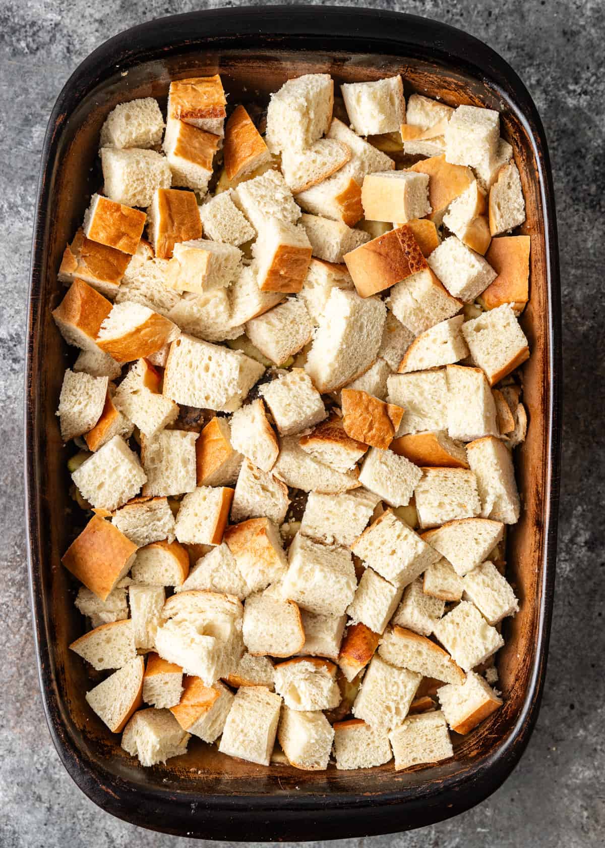 overhead: French toast casserole recipe assembled in a baking dish after adding bread