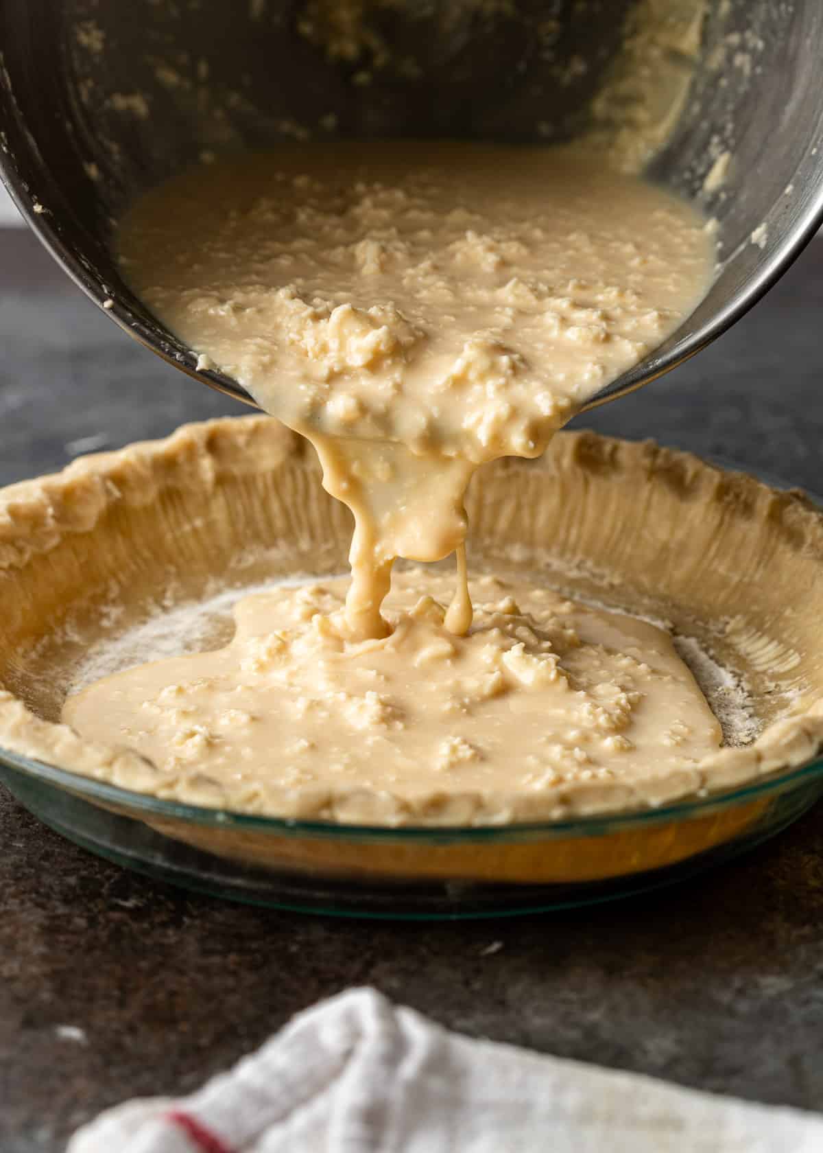 pouring buttermilk pie batter into a prepared pie crust