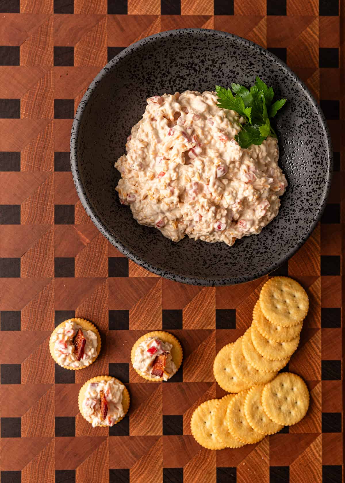 overhead: Southern pâté in a black bowl with Ritz crackers to the side. Some crackers have pimento cheese on them
