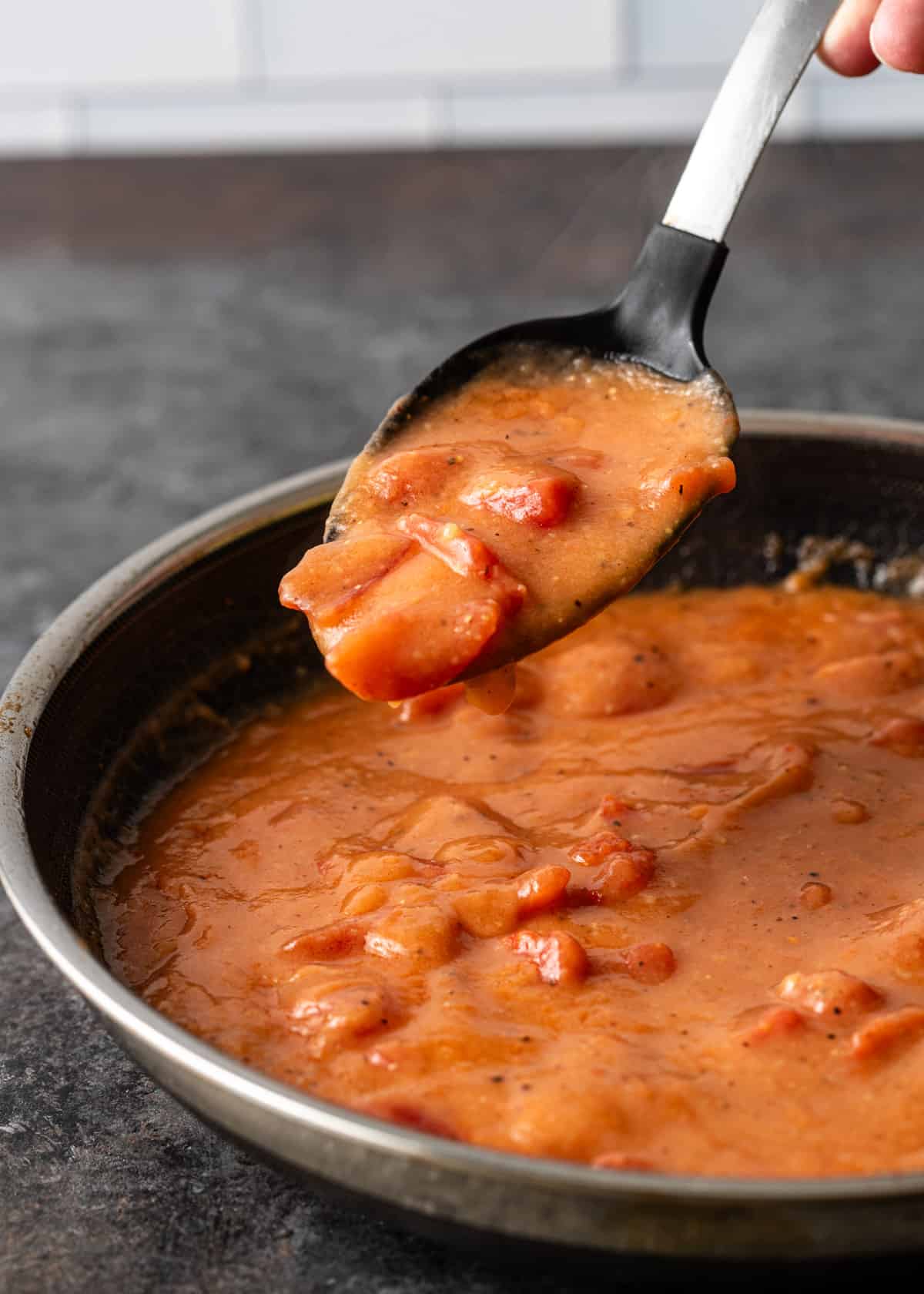 closeup: lifting a spoonful of tomato gravy out of the skillet